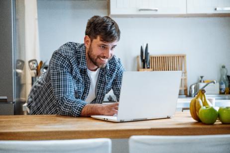 jeune-homme-fait-des recherches-sur-son-ordinateur-depuis-la-cuisine