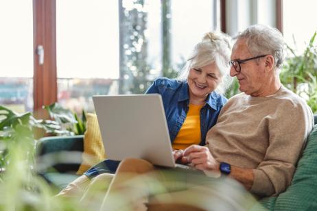 couple de personnes âgées regarde son ordinateur depuis le canapé