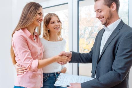 Une femme, accompagnée de sa fille, serre la main d'un agent immobilier à la fin d'une visite pour valider la signature d'un bail de location