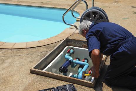 Un homme effectue des réglages sur le système de filtration de sa piscine