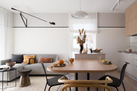 Salon avec canapé gris et table à manger au premier plan. 