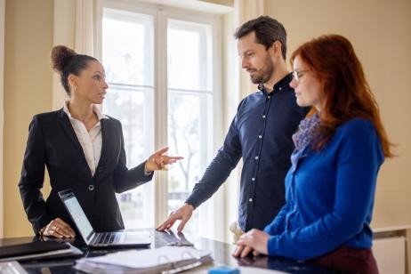 Un couple échange dans le salon avec l'agent immobilier en charge de la vente de son bien immobilier
