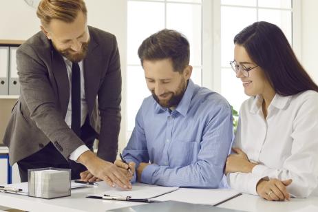 Un couple signe des documents officiels en présence de son notaire