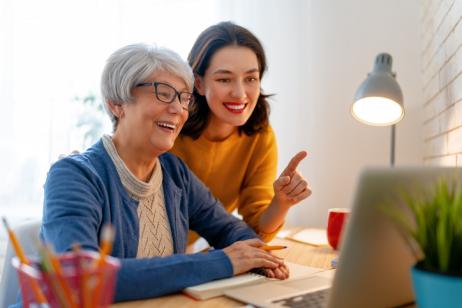 Une mère et sa fille majeure discutent et regardent l'ordinateur sur le bureau. 