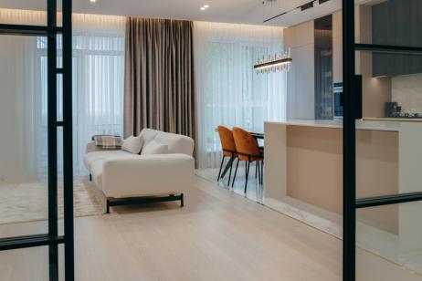 Petit appartement de luxe et décoration épurée avec canapé blanc et portes vitrées. 