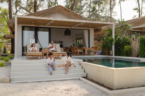 Un couple et ses deux enfants profitent d'une belle villa avec petite terrasse et piscine. 