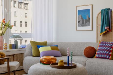 Salon moderne avec un canapé gris et des éléments de déco très colorés. 