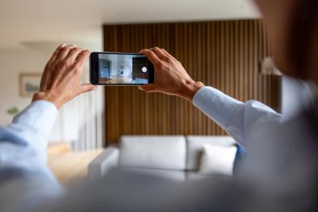 Une femme tourne une vidéo de son appartement avec son téléphone.