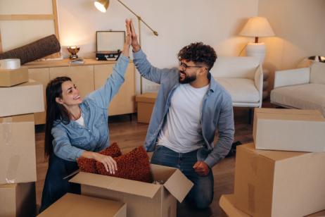 Couple qui se tape dans la main, dans son nouveau salon, entouré de cartons.