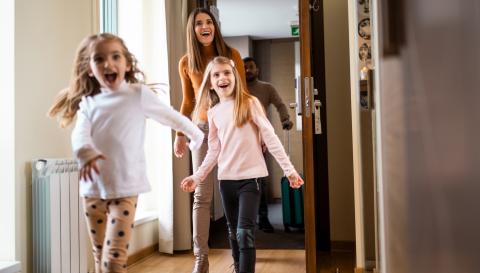 Famille qui sourit et qui rentre dans une maison