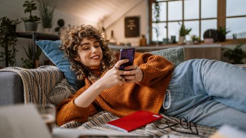 jeune femme sur son téléphone allongé sur son canapé