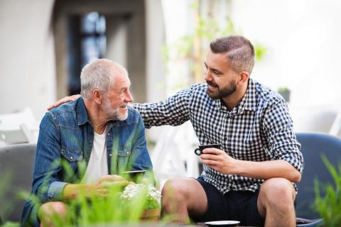 pere et fils prenant un café sur la terrasse de la maison familiale