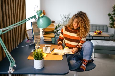 Une jeune femme étudie sur son bureau, dans son studio étudiant.