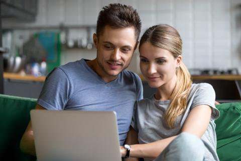 couple regarde son ordinateur avec le sourire 