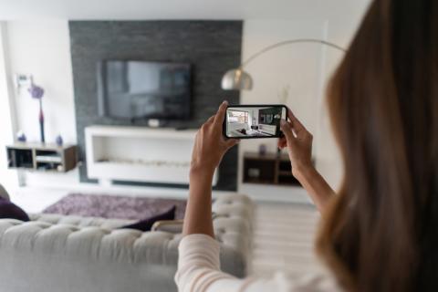 Un agent immobilier femme filme dans le salon avec son téléphone mobile.