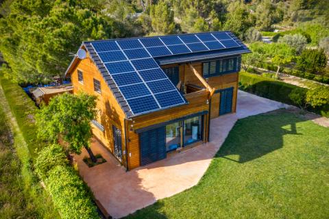 Grande maison avec un toit entièrement recouvert de panneaux solaires. 