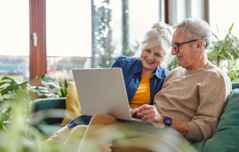 couple de personnes âgées regarde son ordinateur depuis le canapé