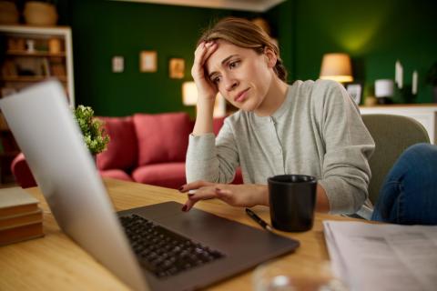 Femme regarde son ordinateur, l'air dépité