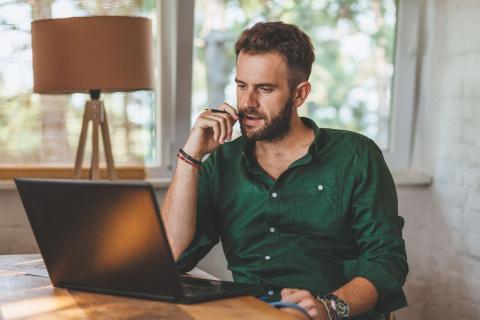 Homme découvre sur son ordinateur les conséquences de la fin de l'amortissement pour les location Airbnb