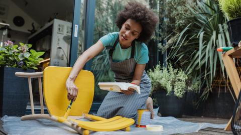 Femme en train de peindre une chaise pour donner une seconde vie à son meuble