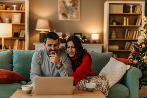 Couple dans son salon décoré pour les fêtes regarde son ordinateur