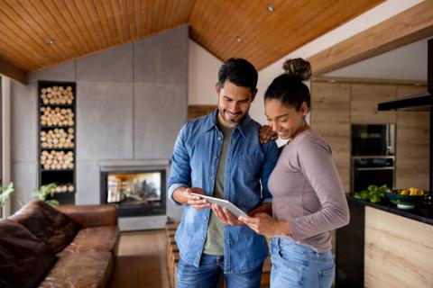 Un couple consulte sa tablette dans le salon cosy. 