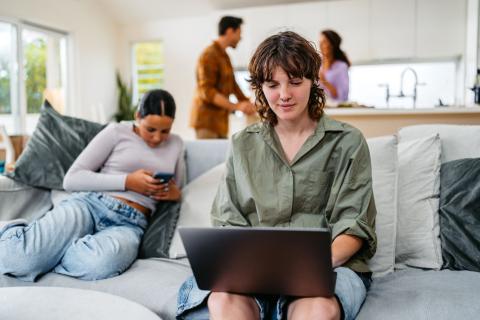 jeune femme regarde son ordinateur dans le salon de sa colocation