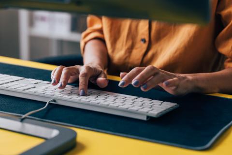 Femme qui tape sur son clavier numérique sur son lieu de travail. 