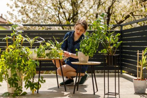 femme en train de s'occuper de ses plantes sur sa terrasse