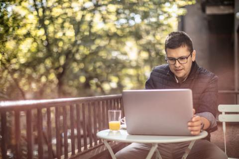 Homme-regarde-son-ordinateur-sur-son-balcon