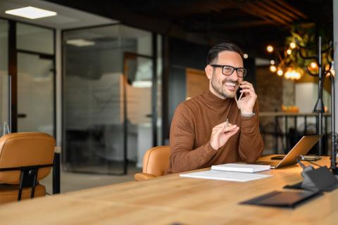 Professionnel qui parle au téléphone dans son bureau aux tons chauds.
