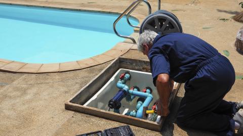 Un homme effectue des réglages sur le système de filtration de sa piscine