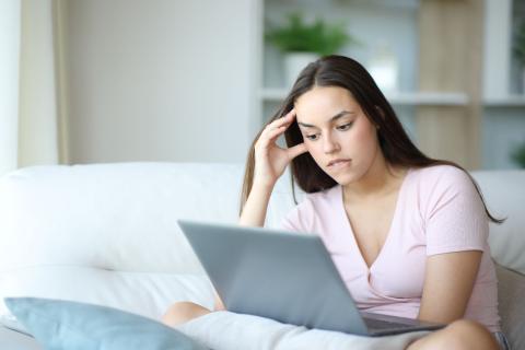 jeune femme regarde son ordinateur l'air inquiet