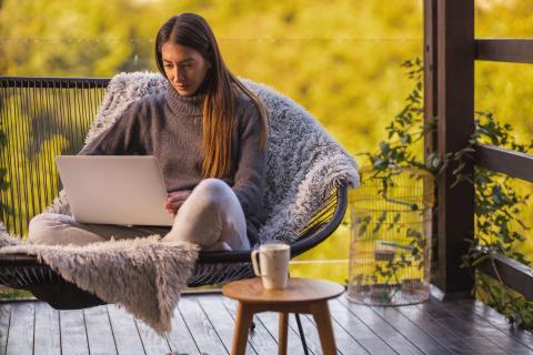 femme-regarde-son-ordinateur-sur-le-canape-de-son-balcon