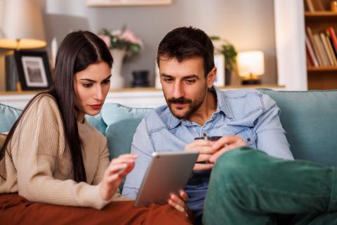 couple recherche sur sa tablette le montant minimum de l'apport pour acheter une maison 