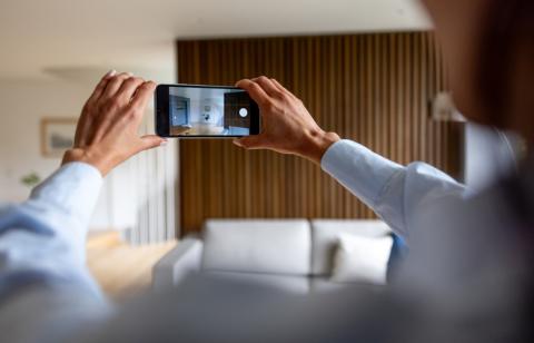 Une femme tourne une vidéo de son appartement avec son téléphone.