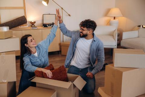 Couple qui se tape dans la main, dans son nouveau salon, entouré de cartons.