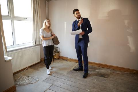 Female First Time Buyer Looking At House Survey With Realtor