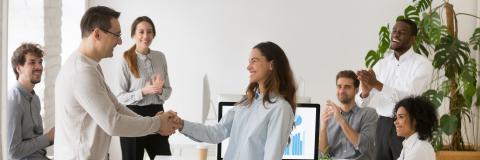 Boss handshaking with mixed race female employee congratulating with success