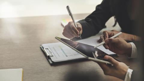 Closeup shot business consult with tablet and paperwork.