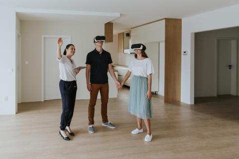 Estate agent with young couple wearing VR headsets in new apartment