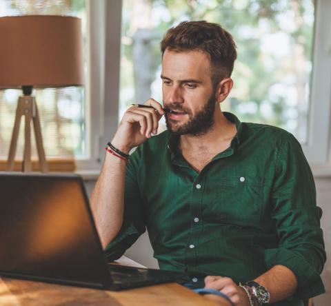 Homme découvre sur son ordinateur les conséquences de la fin de l'amortissement pour les location Airbnb