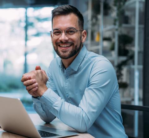 Un agent immobilier souriant devant son ordinateur. 