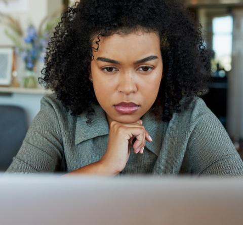 Femme qui réfléchit devant son ordinateur. 