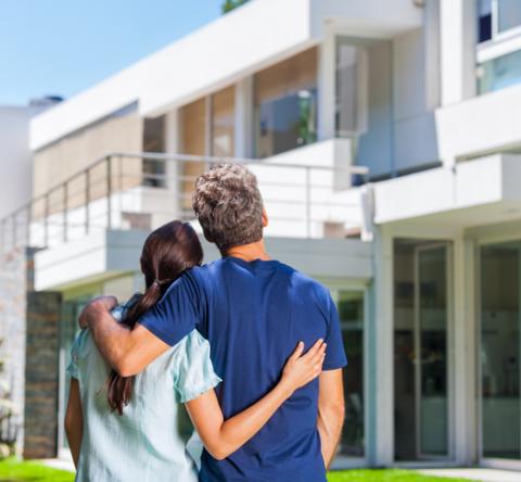 Un couple regarde la maison qu'il convoite de l'extérieur. 