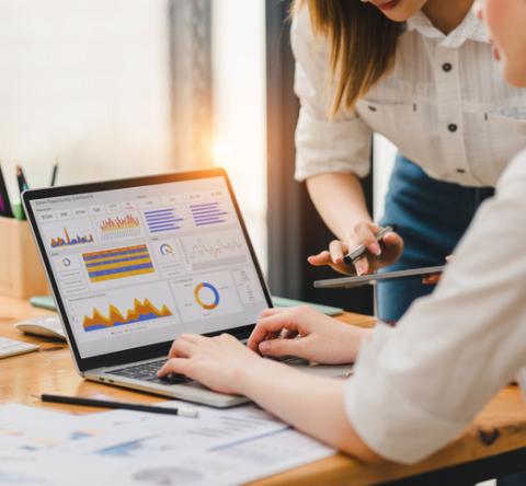 Deux femmes consultent les tableaux de bord de leur CRM sur un ordinateur. 