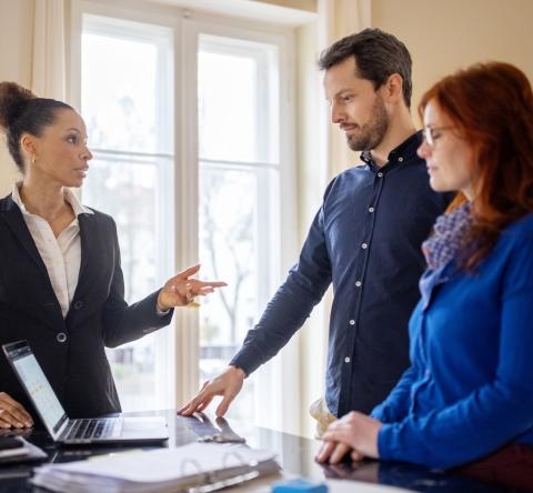 Un couple échange dans le salon avec l'agent immobilier en charge de la vente de son bien immobilier