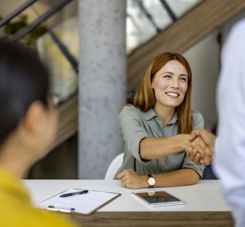 Agent immobilier femme souriante qui serre la main de son client. 