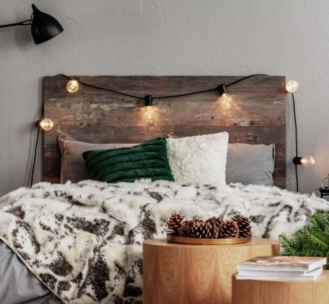 Chambre à la déco chaleureuse avec tête de lit en bois et guirlande lumineuse