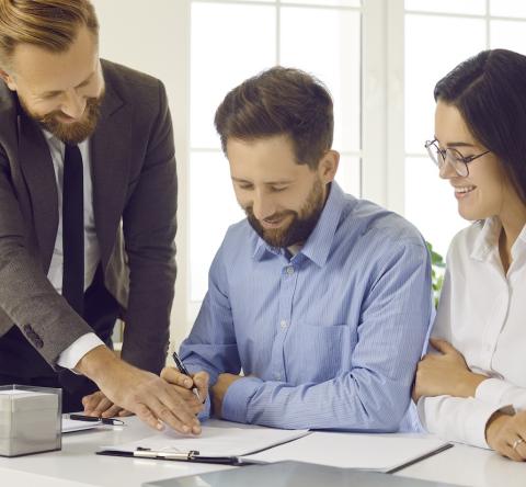 Un couple signe des documents officiels en présence de son notaire